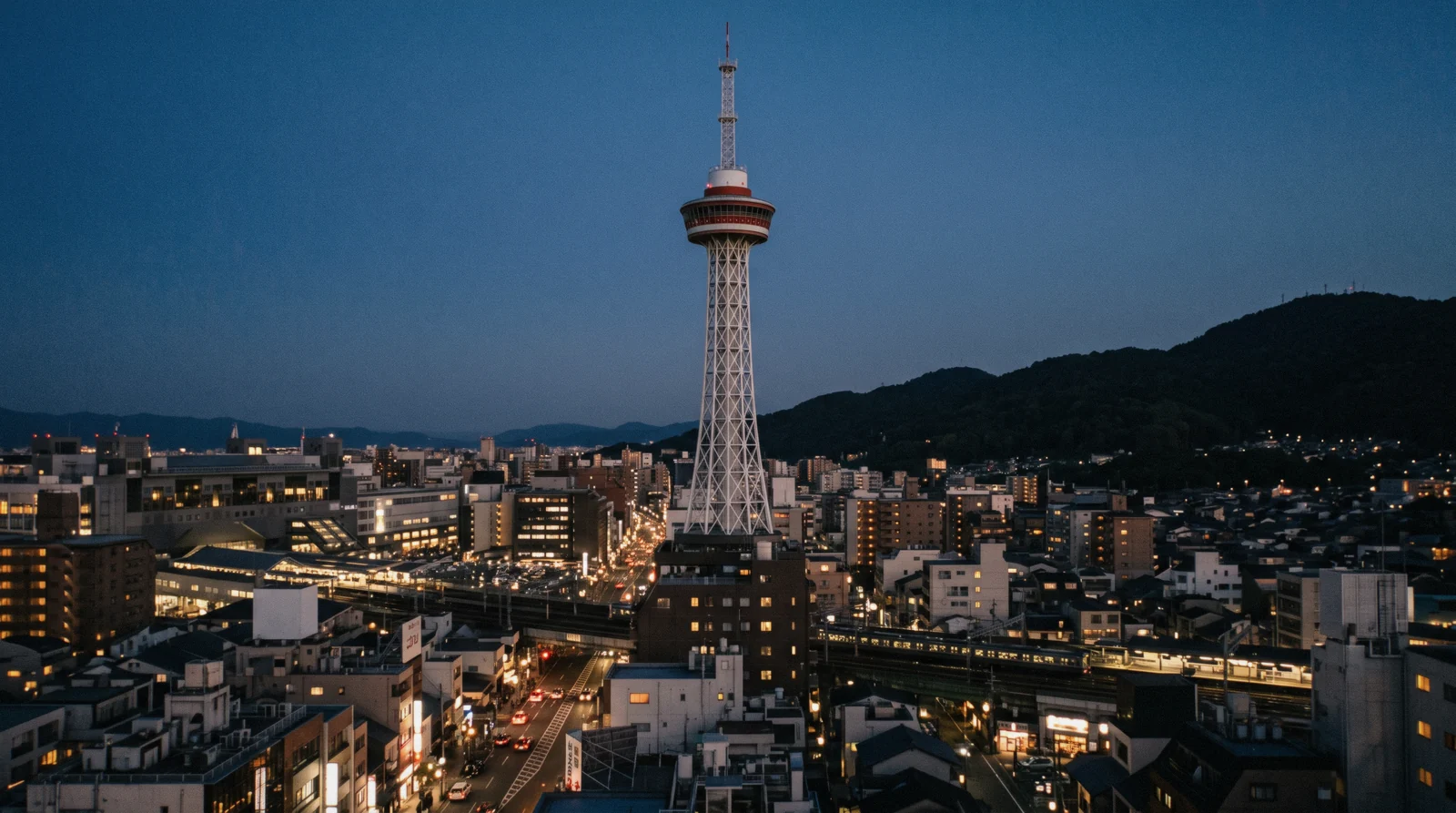 The white lattice of Kyoto Tower rising above the station district at dusk, Kyoto Japan