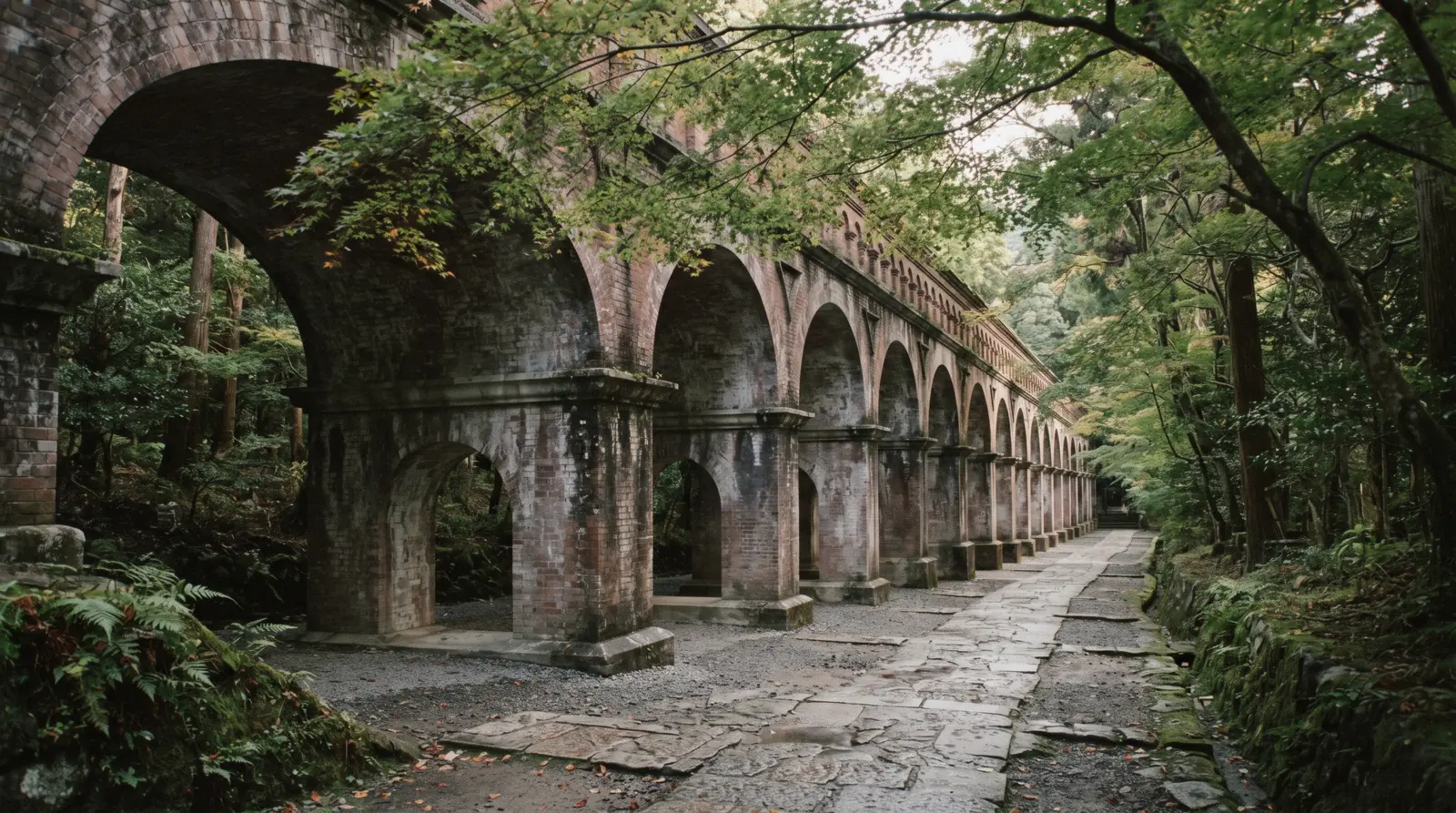 The brick arches of the Suirokaku aqueduct running through the temple grounds under maples, Nanzen-ji Kyoto Japan