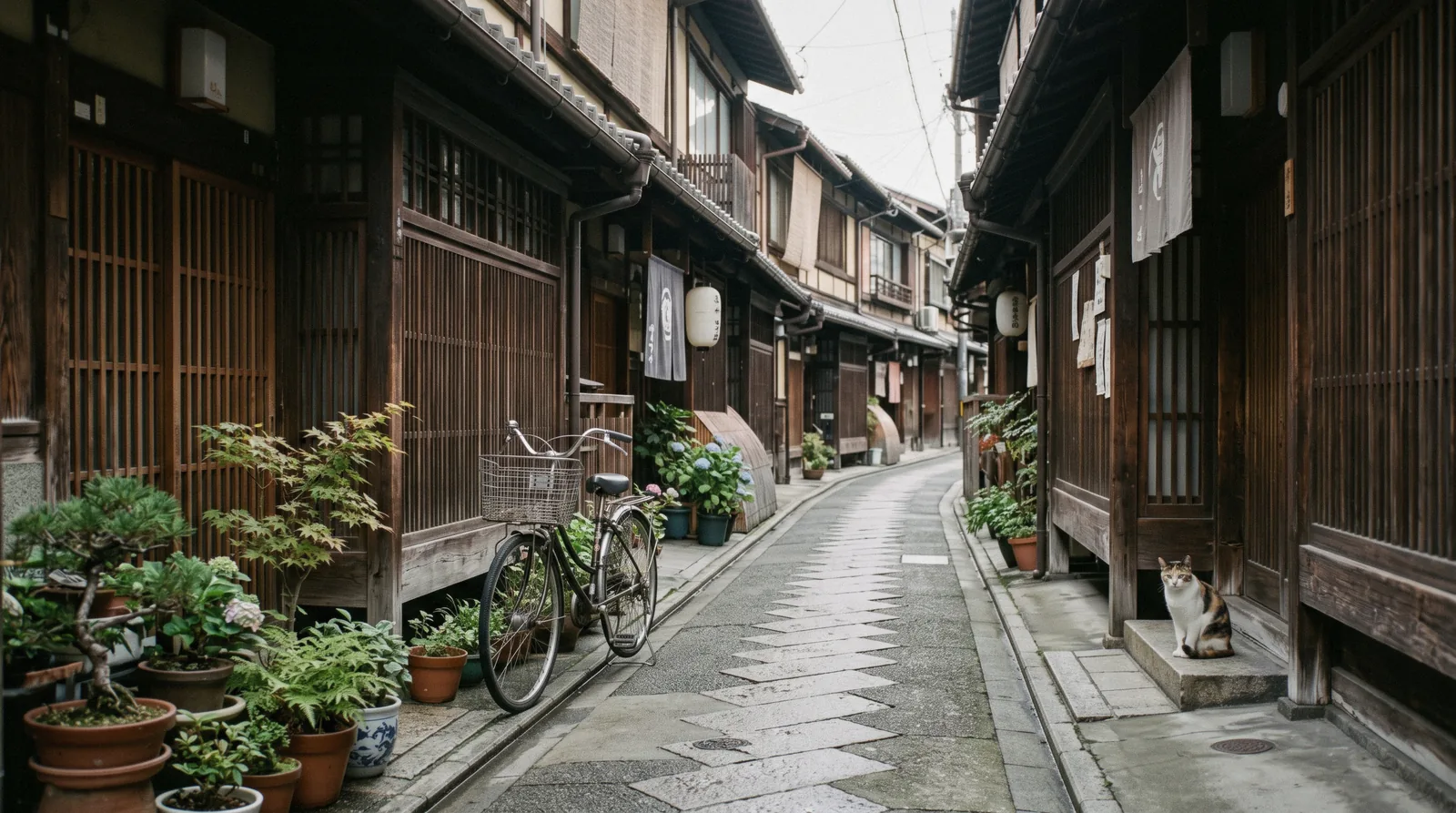 A quiet Kyoto side street of machiya houses at dawn with a bicycle against a wall, planning a Kyoto trip Japan