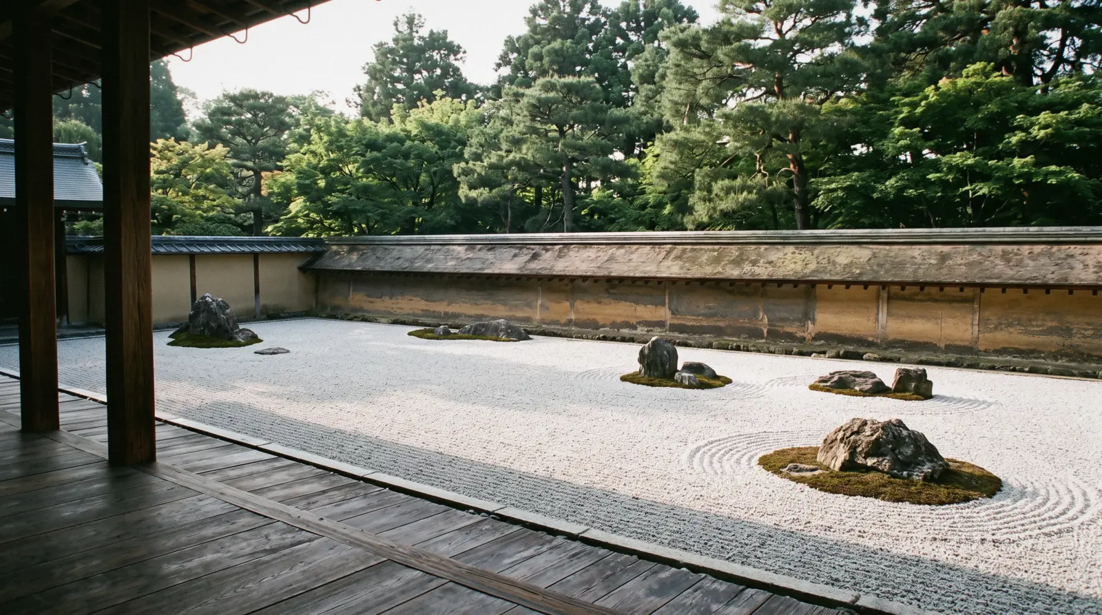 The fifteen rocks and raked white gravel of the Ryoan-ji dry garden below its ochre wall, Kyoto Japan