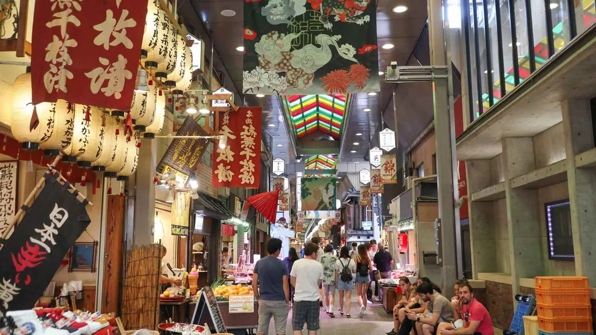 Stallholder serving a tasting in the covered arcade of Nishiki Market, Kyoto Japan