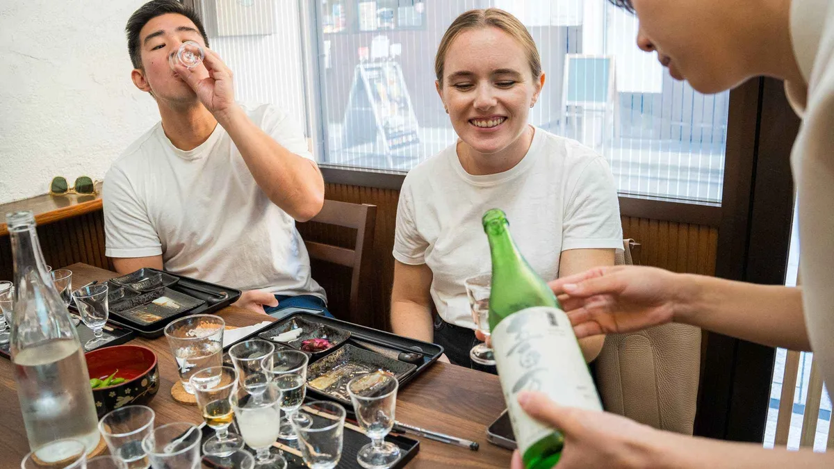 Flight of seven sake glasses with snacks at a Kyoto tasting, Kyoto Japan