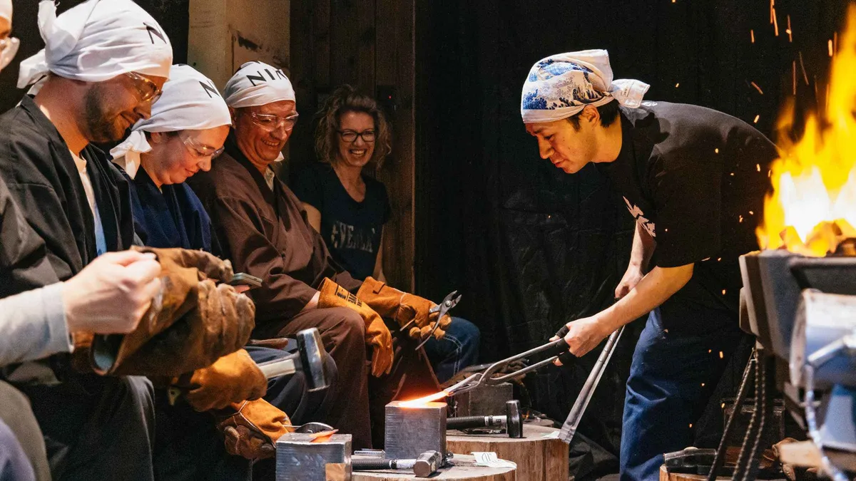 Blacksmith and participant forging a blade at a knife-making workshop in Kyoto, Kyoto Japan